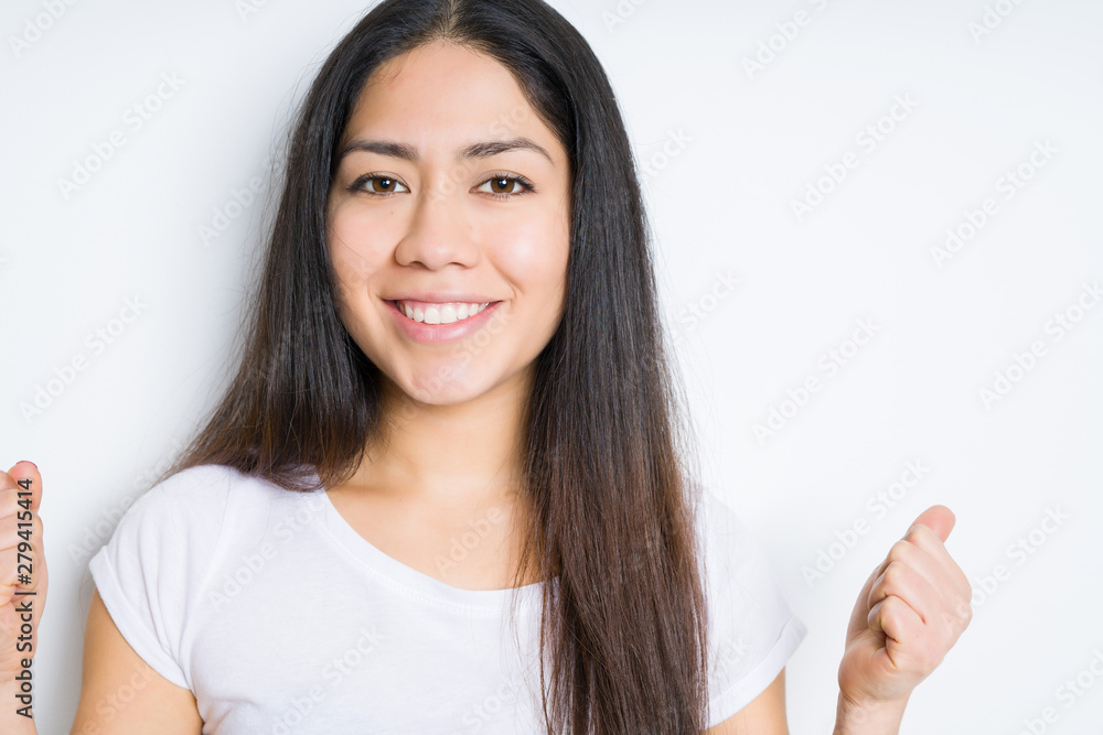 Beautiful brunette woman over isolated background celebrating surprised and amazed for success with arms raised and open eyes. Winner concept. Beautiful brunette woman over isolated background celebrating surprised and amazed for success with arms raised and open eyes. Winner concept.