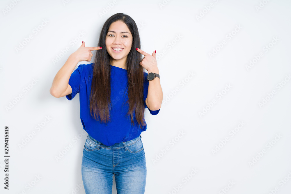 Beautiful brunette woman over isolated background smiling confident showing and pointing with fingers teeth and mouth. Health concept. Beautiful brunette woman over isolated background smiling confident showing and pointing with fingers teeth and mouth. Health concept.