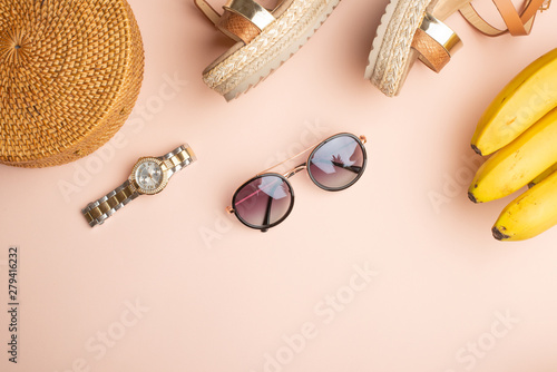 Summer background with a wicker fashionable bag, and women's summer shoes, and sun glasses, watches. Summer fashion, the concept of a holiday. Fly lay.Banner