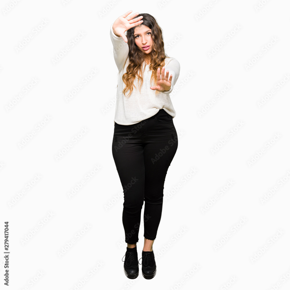 Young beautiful woman wearing white sweater Smiling doing frame using hands palms and fingers, camera perspective Young beautiful woman wearing white sweater Smiling doing frame using hands palms and fingers, camera perspective