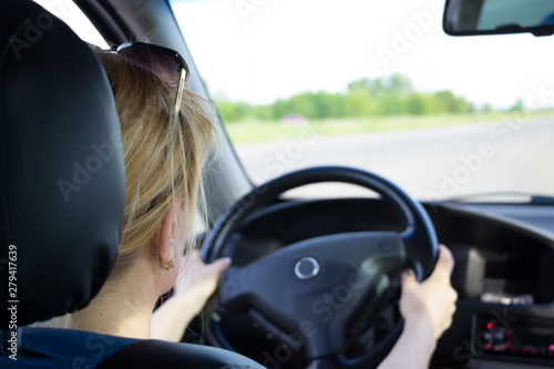 Young woman driving car on a highway. View from the back.