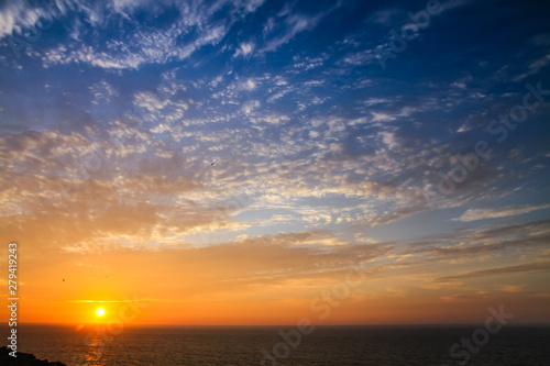 Sunset above the sea landscape panorama with full yellow sun reflections over the Atlantic Ocean and beautiful blue sky with white clouds seen from Sagres  Portugal.
