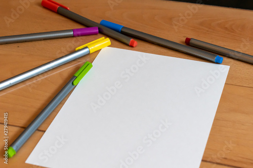 Color markers and white sheet of paper on bright modern wooden desk