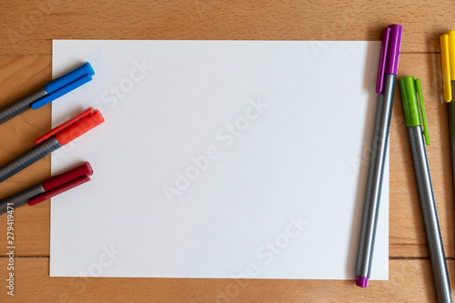 Color markers and white sheet of paper on bright modern wooden desk