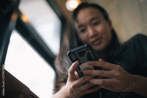 Happy smiling Asian woman holds mobile phone, close up focus on female hands and device. Customer buying goods via internet, friends chatting online, generation addicted with gadgets concept