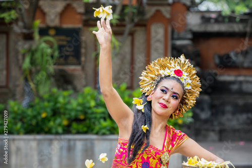 Female Pendet dancer throwing frangipani flower photo