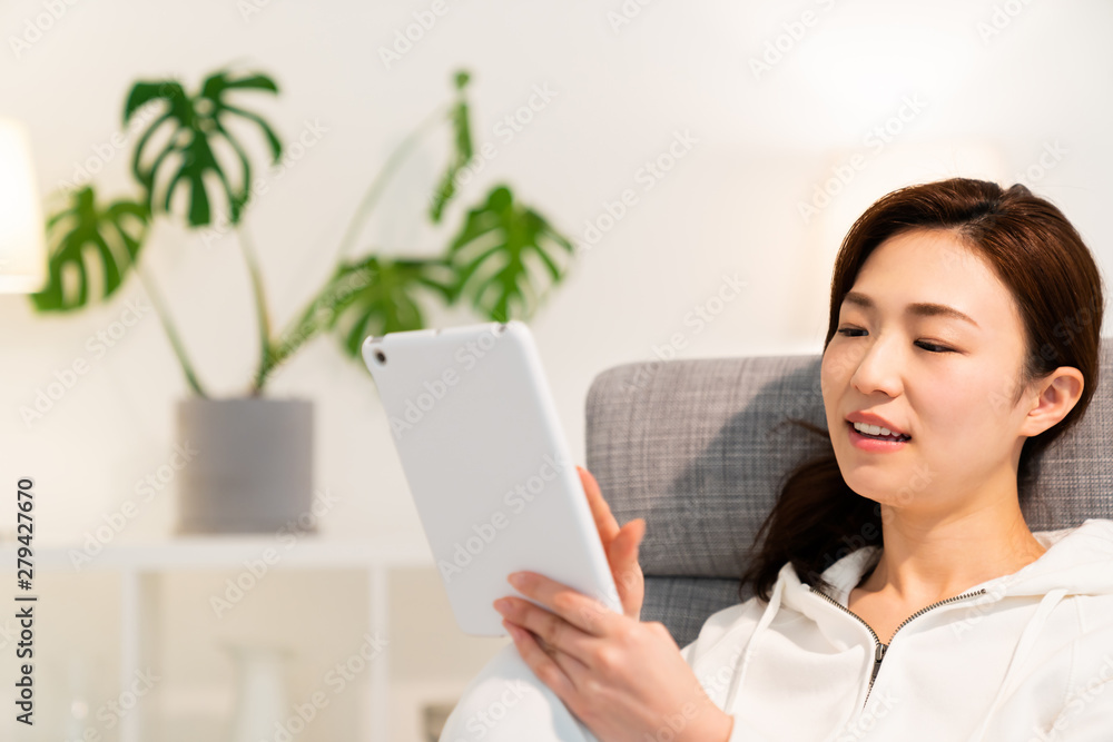 部屋でタブレットを見る女性