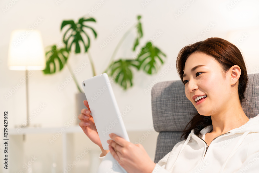 部屋でタブレットを見る女性