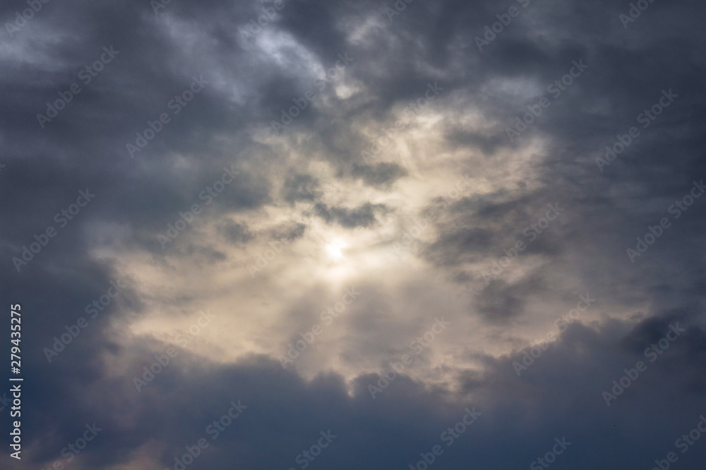 The sky with dark stormy clouds, through which the sun looks_