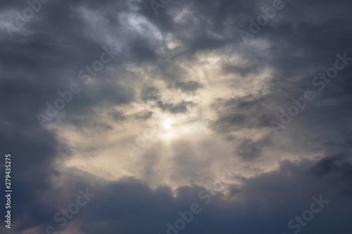 The sky with dark stormy clouds, through which the sun looks_