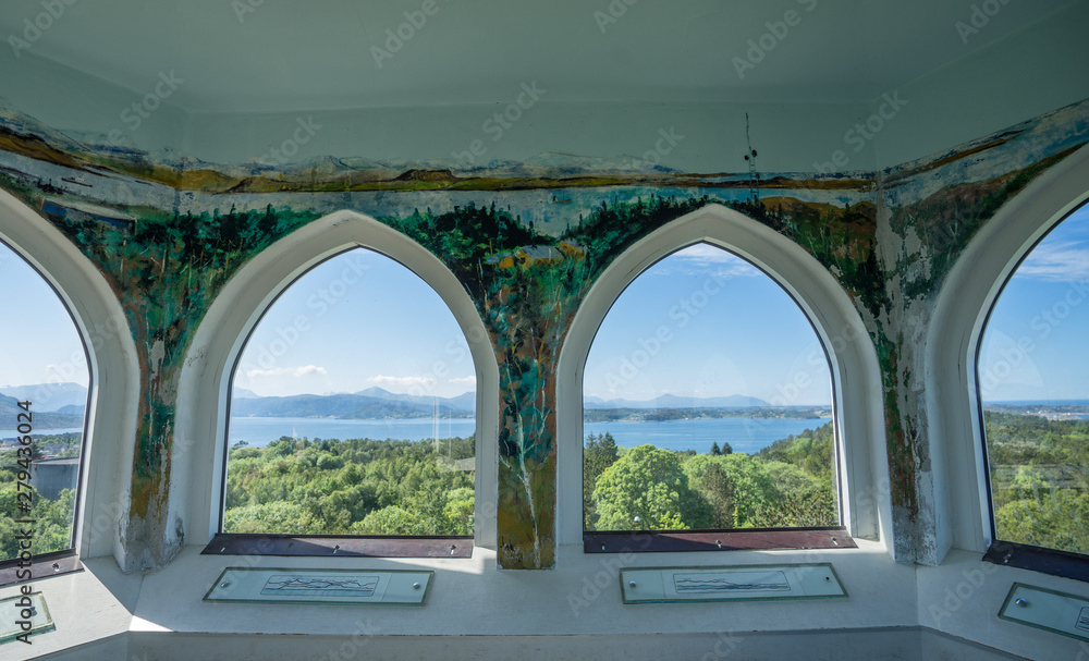 Obraz premium Kristiansund / Norway - June 15 2019: Interior of the Varden viewpoint, the highest point on Kirkelandet. Decorated wall inside, 360 degrees view via arched windows on surrounding mountains and fjord.