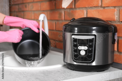 Woman washing modern multi cooker in kitchen sink, selective focus