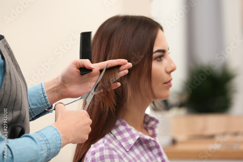 Barber making stylish haircut with professional scissors in beauty salon