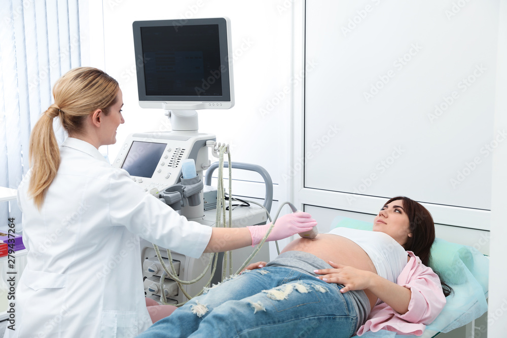 Obraz premium Young pregnant woman undergoing ultrasound scan in modern clinic