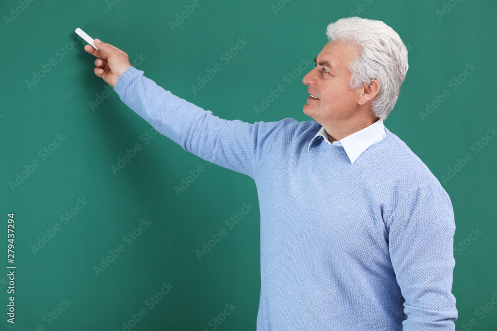 Portrait of senior teacher with chalk at green board