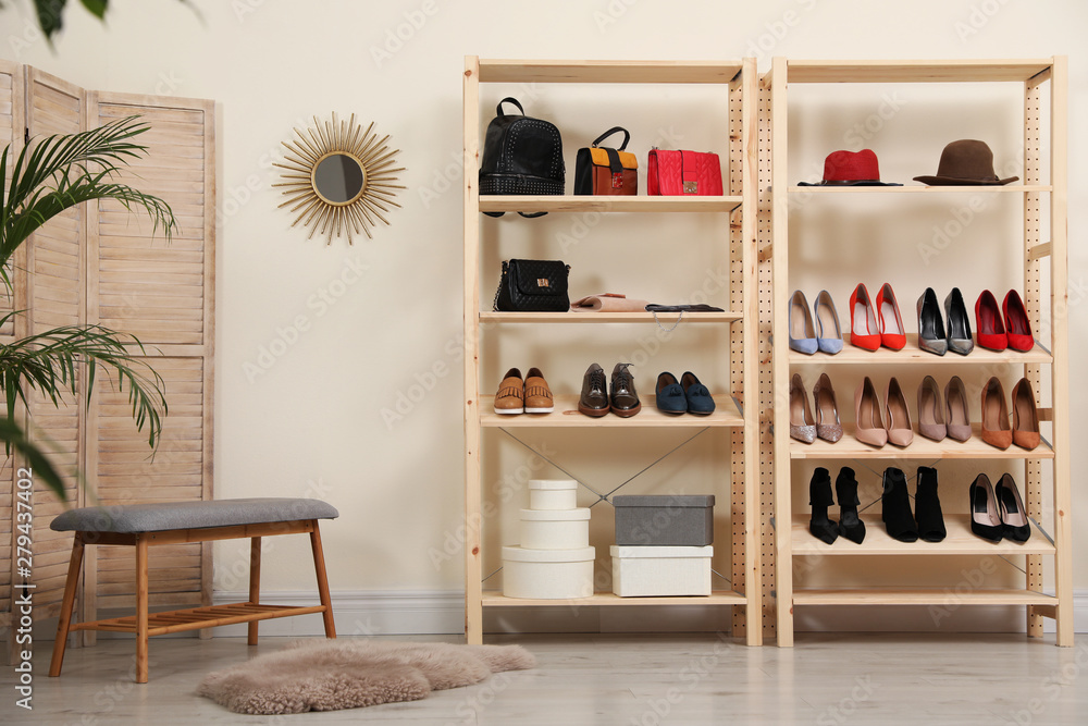 Wooden shelving unit with different shoes and accessories in stylish room interior
