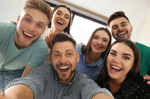 Group of happy people taking selfie in office