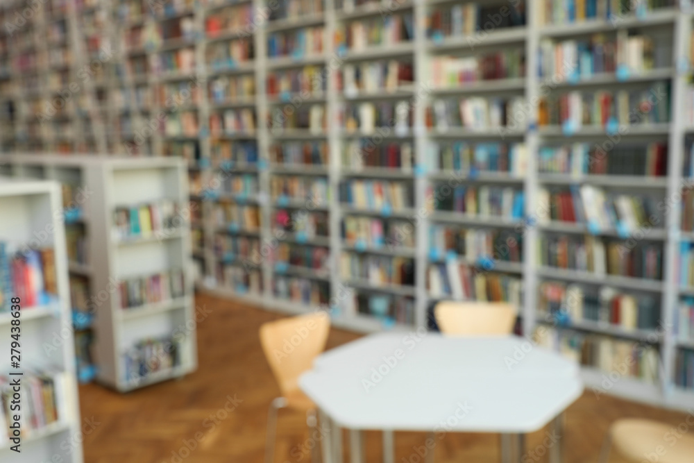 Blurred view of bookshelves and table in library Blurred view of bookshelves and table in library