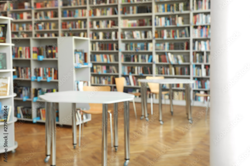 Blurred view of bookshelves and tables in library