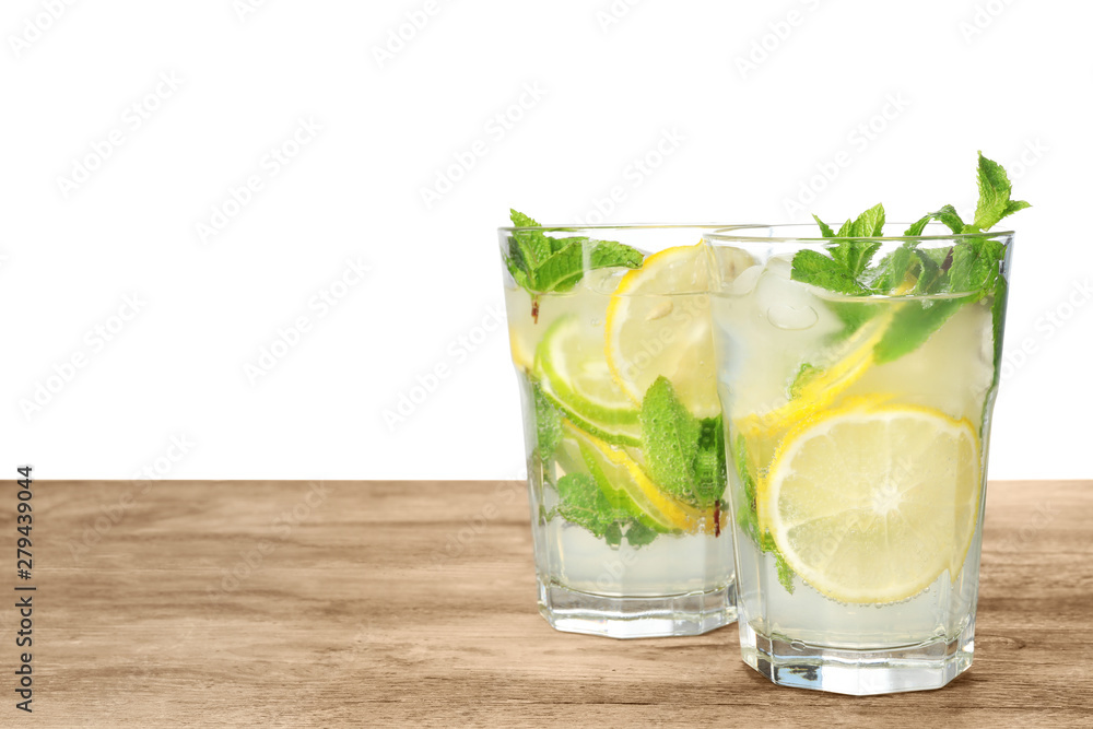 Glasses of refreshing drink with citrus slices and mint on wooden table against white background