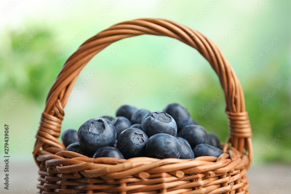 Wicker basket with fresh blueberries on blurred green background, closeup Wicker basket with fresh blueberries on blurred green background, closeup
