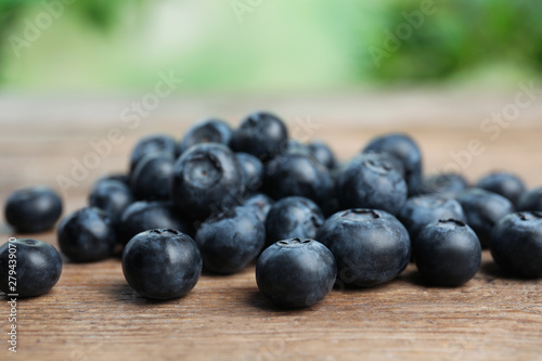 Pile of tasty fresh blueberries on wooden table, closeup