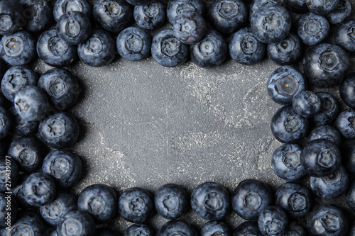 Frame made with fresh blueberries on grey table, top view. Space for text