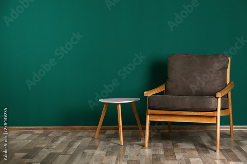 Stylish room interior with armchair and side table near color wall, space for text