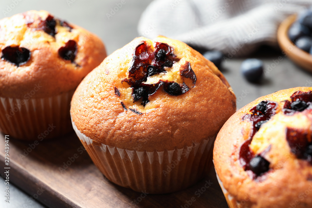 Tasty blueberry muffins on wooden board, closeup view Tasty blueberry muffins on wooden board, closeup view