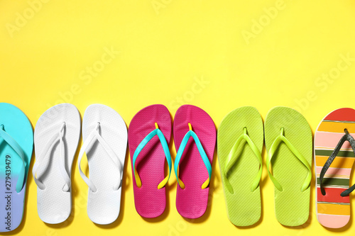 Different flip flops and space for text on yellow background, flat lay. Summer beach accessories