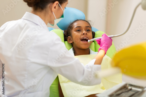 Dark-haired woman doctor leaning over a young patient