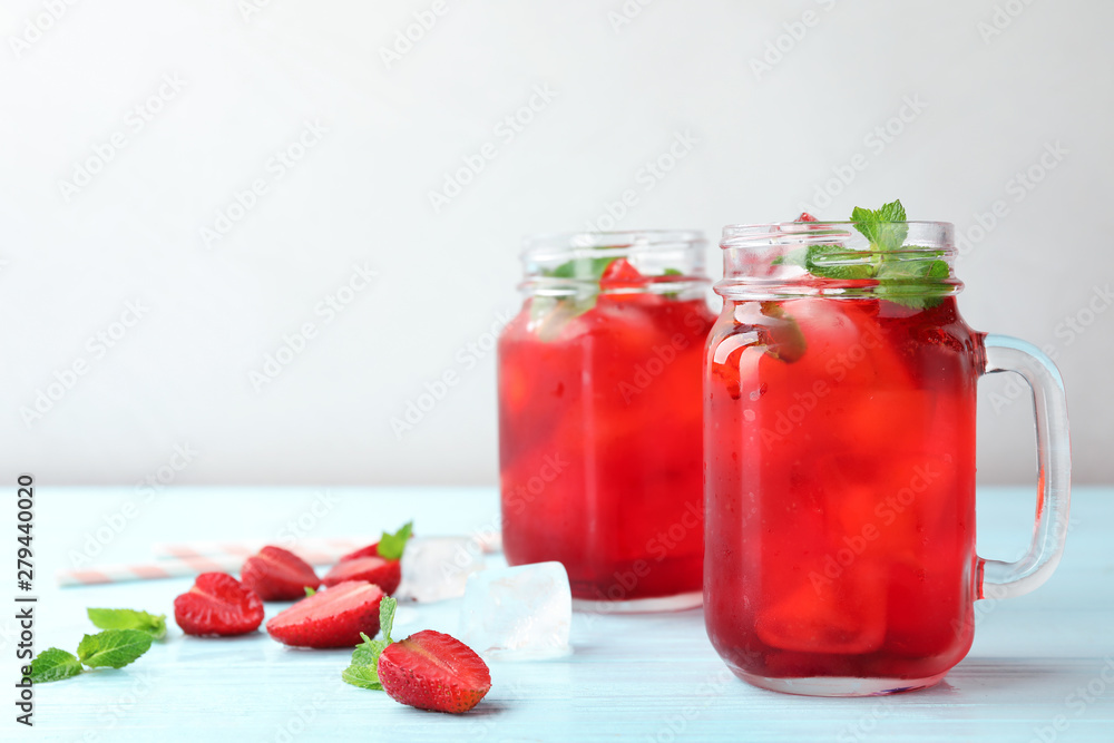 Mason jars with strawberry refreshing drink on light blue wooden table, space for text Mason jars with strawberry refreshing drink on light blue wooden table, space for text