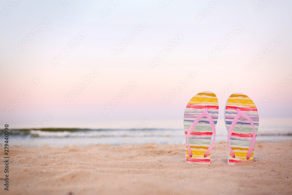 Obraz premium Stylish flip flops on sand near sea, space for text. Beach accessories