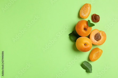 Delicious ripe sweet apricots on green background, flat lay. Space for text