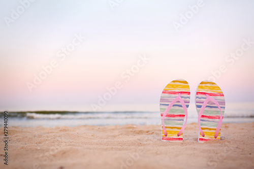 Stylish flip flops on sand near sea  space for text. Beach accessories