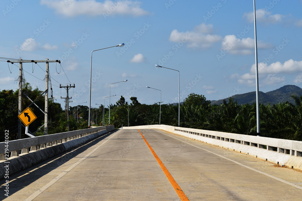 Fototapeta premium Open road on the bridge with mountain and blue sky in background, Southeast Asia, Thailand