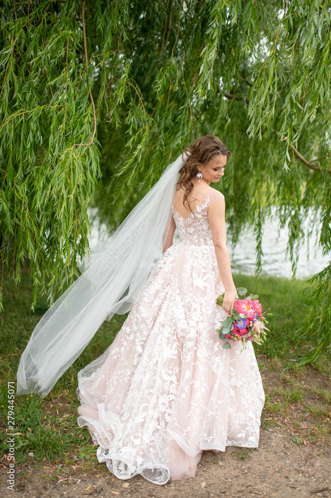 Beautiful young bride in white wedding dress posing outdoor with bouquet of flowers. Beautiful young bride in white wedding dress posing outdoor with bouquet of flowers.