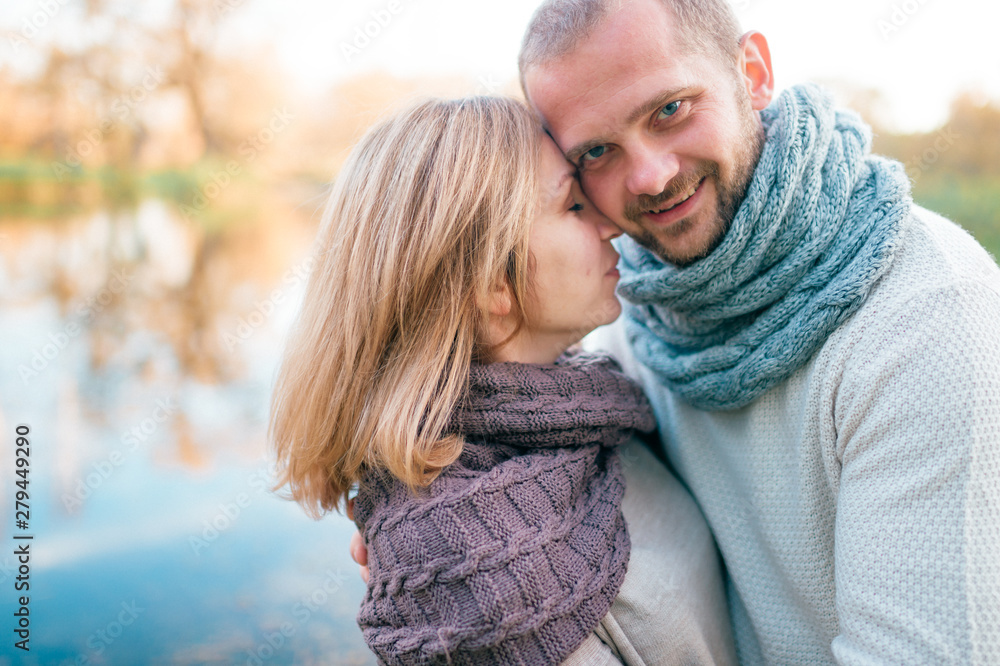 Fototapeta premium Loving couple in knitted clothes romantic portrait with reflected lake on background.