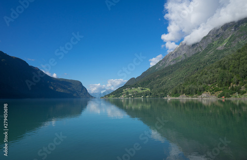 Panoramic view of The Sognefjord (Sognefjorden), nicknamed the King of the Fjords. Te largest and deepest fjord in Norway. Symmetry created by reflections in the still ocean water. Bright midsummer. © Ingrid