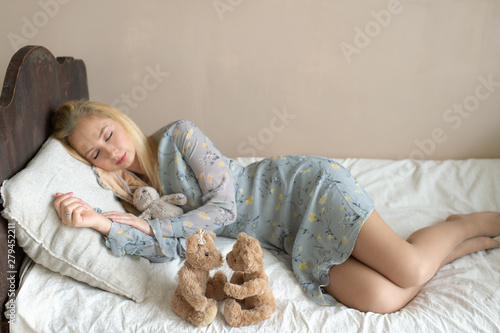 Young beautiful girl sleeping on bed with kid toys like child.