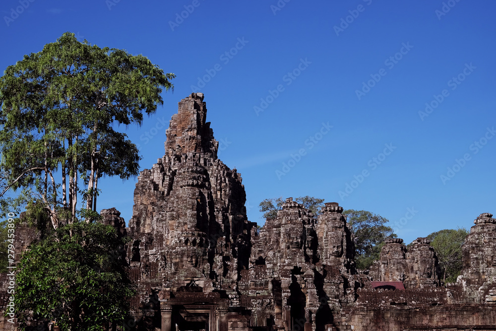 The majestic towers of Bayon Temple, in Cambodia. Tall tropical trees. Beautiful landscape.