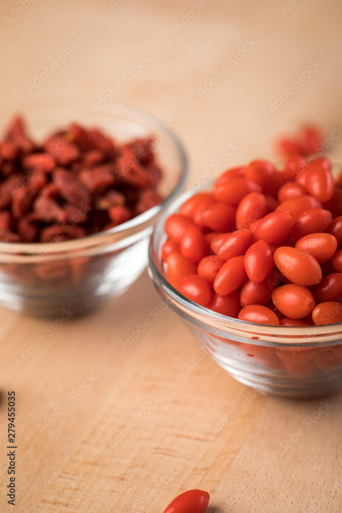 Frische und getrocknete Goji-Beeren Superfood in Glas Schale auf Holz Brett Hintergrund Frische und getrocknete Goji-Beeren Superfood in Glas Schale auf Holz Brett Hintergrund
