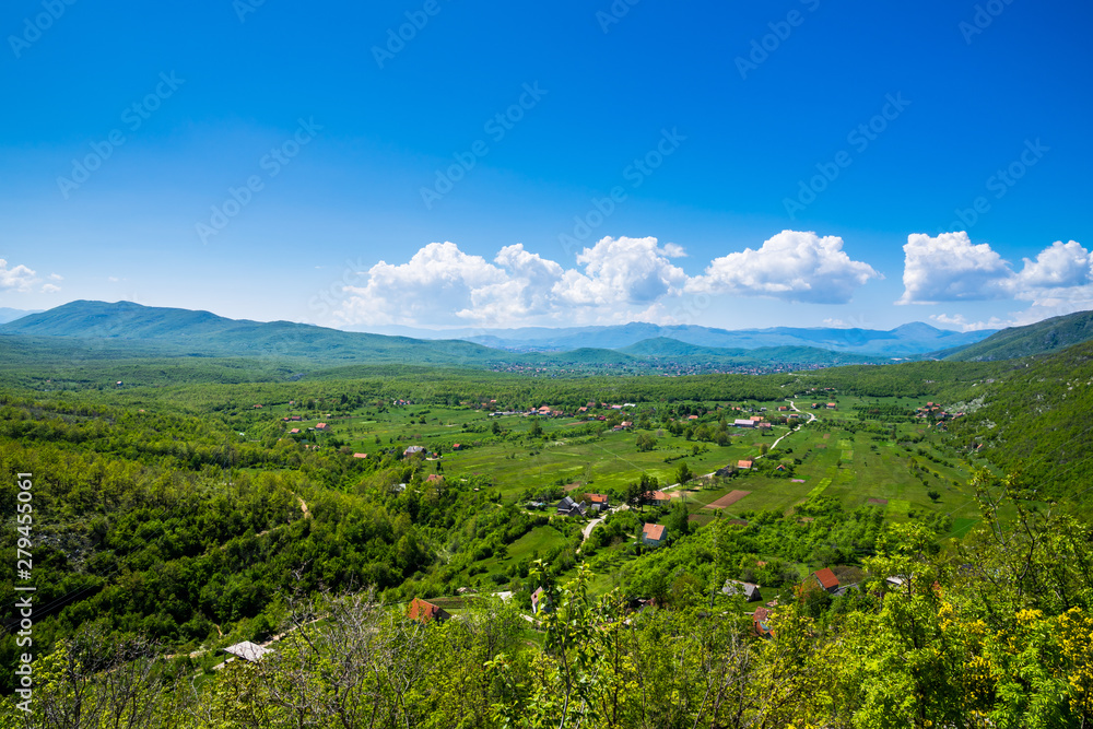 Montenegro, Houses of vidrovan village in green valley surrounded by mountains and forest in country scenery of nature landscape with blue sky in springtime
