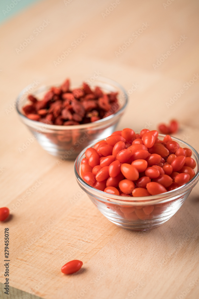 Frische und getrocknete Goji-Beeren Superfood in Glas Schale auf Holz Brett Hintergrund Frische und getrocknete Goji-Beeren Superfood in Glas Schale auf Holz Brett Hintergrund