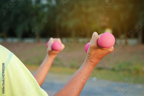 An elderly woman is an Asian Raise the pink dumbbell to exercise for health in the garden.