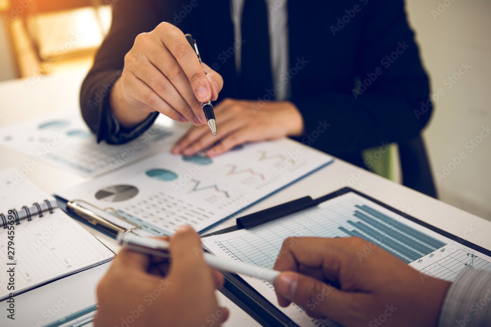 Two business partnership coworkers analysis cost work progress and gesturing with discussing a financial planning graph and company financial during a budget meeting in office room. Two business partnership coworkers analysis cost work progress and gesturing with discussing a financial planning graph and company financial during a budget meeting in office room.