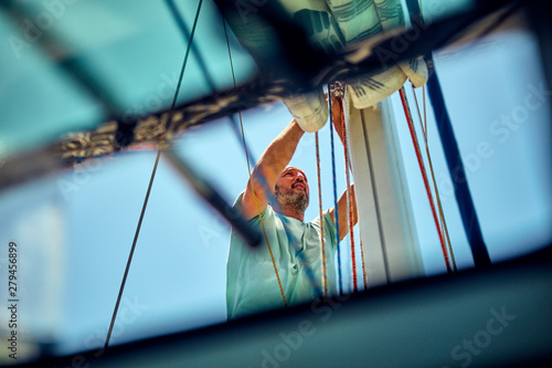 Tableau sur toile Sailor packing / unpacking main sail wing on the boat.