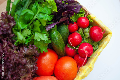 cucumbers  tomatoes  radishes  lettuce  basil  parsley in a box with a yellow napkin. space for text