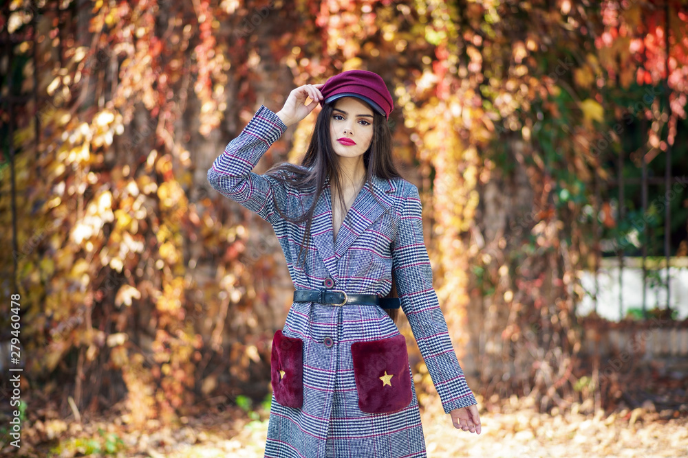 Young beautiful girl wearing winter coat and cap in autumn leaves background. Young beautiful girl wearing winter coat and cap in autumn leaves background.