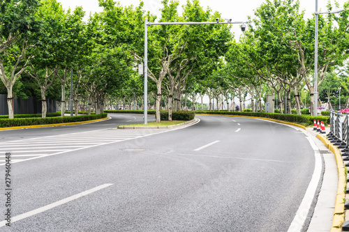 Asphalt road under green trees